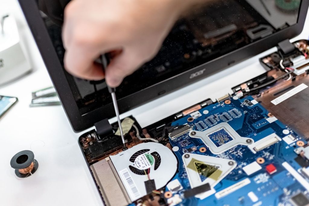 Technician repairing the inside of a laptop with a screwdriver