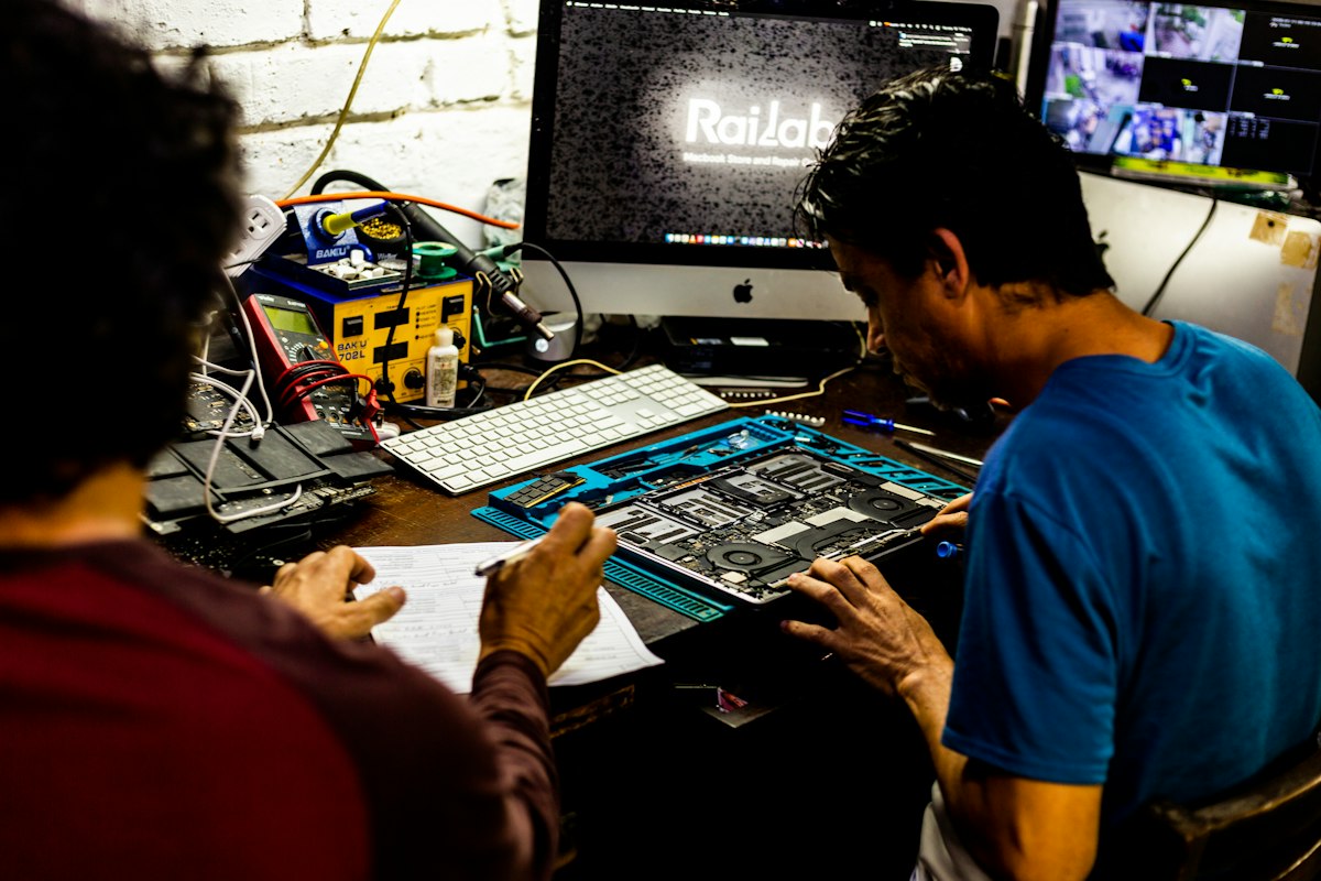 Two technicians repairing a computer at a workbench